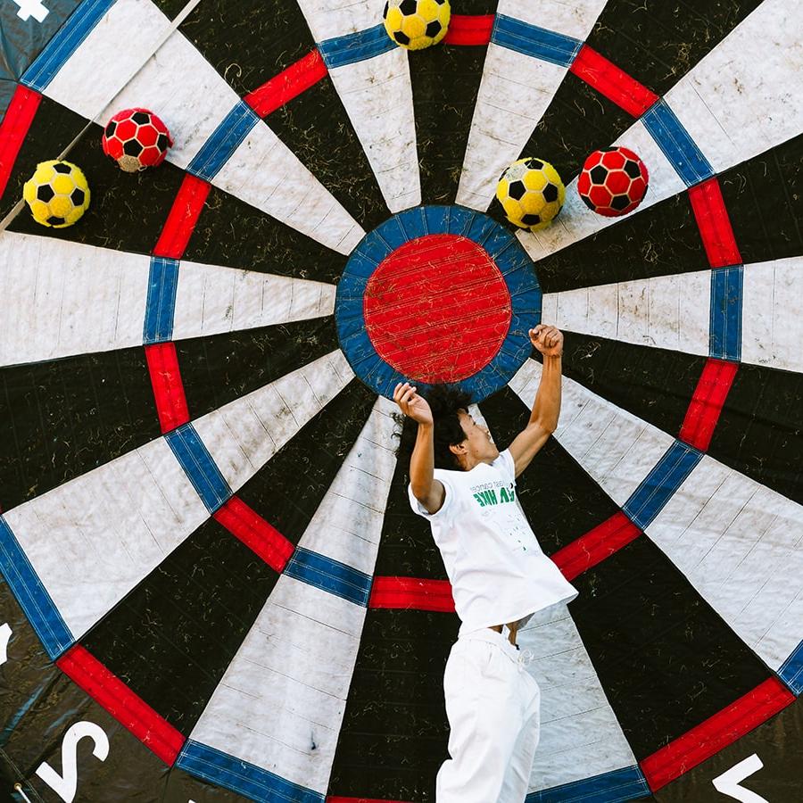 student jumps in air against a giant velcro wheel with balls sticking to it