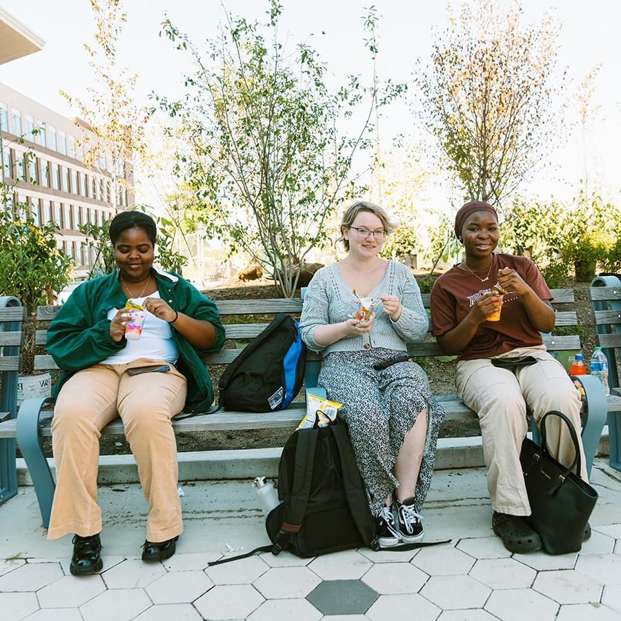 students sit on benches in quad eating treats